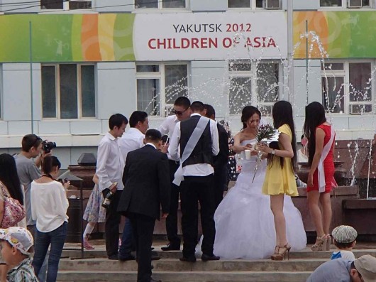 A wedding party celebrates a toast at the fountain in the Yakutsk plaza.