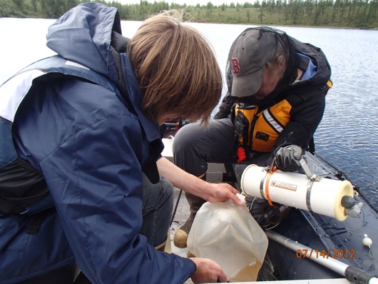 Vasily and Karen work together to fill a sampling jug.