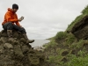 Sam Dunn examines a vertebrae near an eroding riverbank.